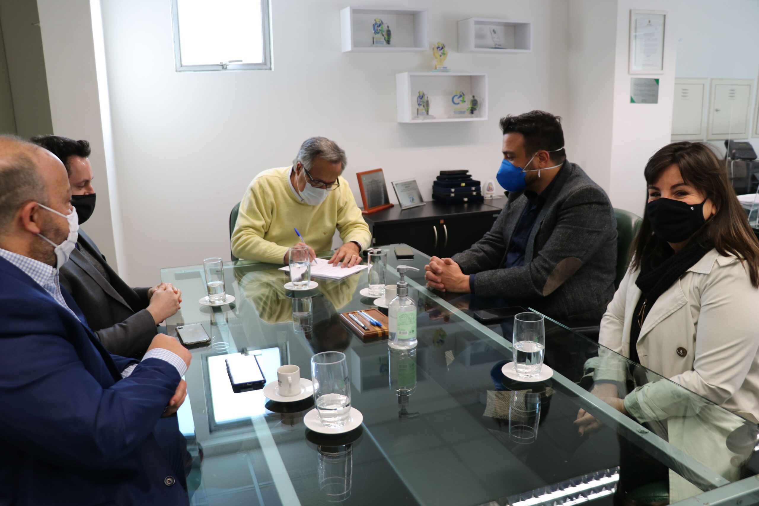 Presidente do CRMV-SP assina protocolo de intenções na presença de representantes do Sebrae. Estão todos sentados à mesa de máscara, olhando o presidente assinar o protocolo.