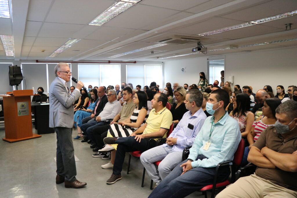 Presidente do CRMV-SP está posicionado de pé a frente de um auditório lotado com colaboradores sentados prestando atenção na apresentação dos resultados 2022.