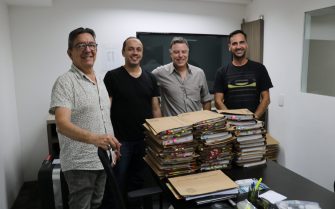 Membros da Comissão de Tomada de Contas do CRMV_SP posam para foto com as pilhas de processos em papel