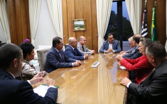 Nove representantes do CRMV-SP, sendo duas mulheres, estão sentados ao entorno de uma mesa retangular de madeira. Na cabeceira, está o vice-governador. Ao fundo, estão as bandeiras do estado de São Paulo e do Brasil.